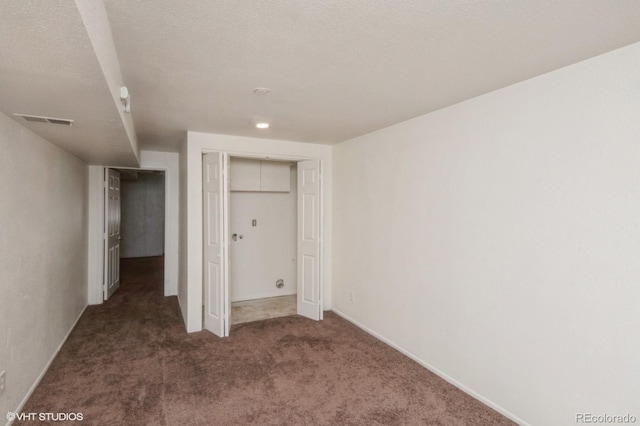 unfurnished bedroom featuring a closet, dark carpet, and a textured ceiling