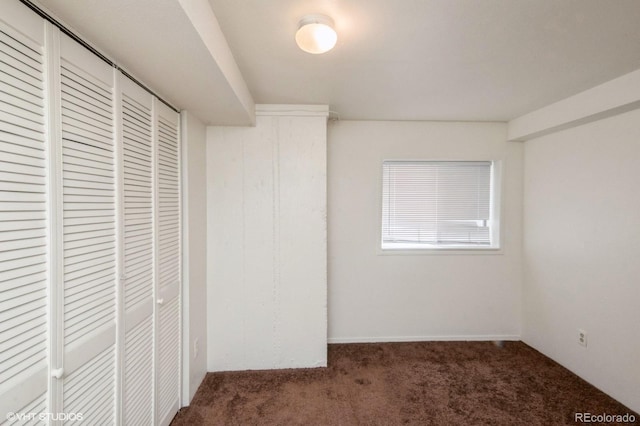 unfurnished bedroom featuring a closet and dark carpet