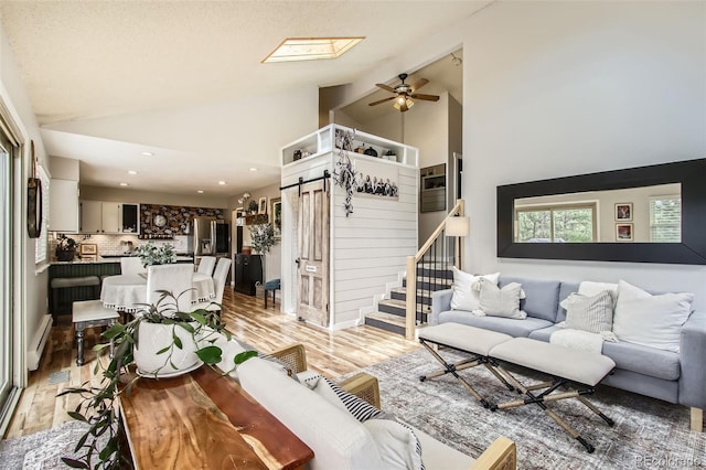 16626 Ouray Rd W, Pine, CO 80470 - living room featuring a baseboard radiator, ceiling fan, light wood-type flooring, a barn door, and stairs