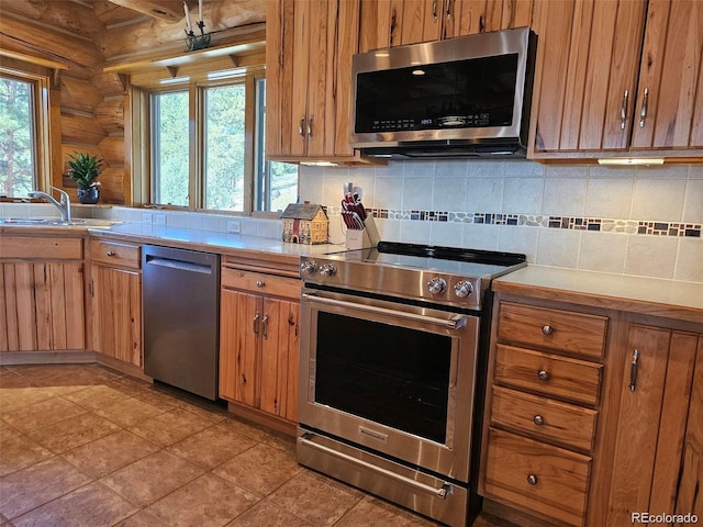 kitchen with a healthy amount of sunlight, sink, stainless steel appliances, and log walls