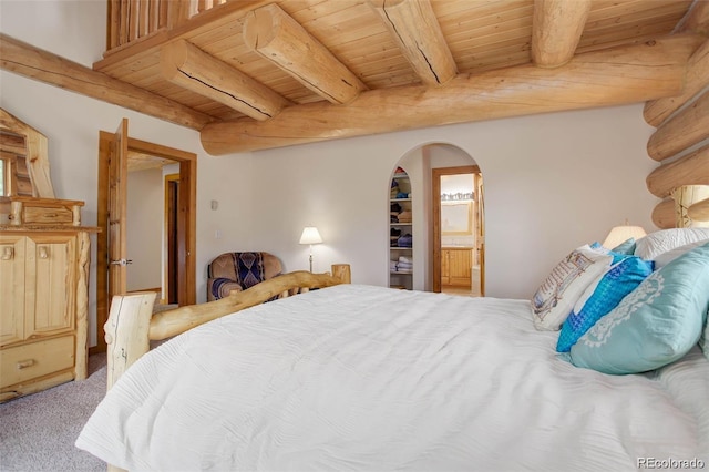 bedroom featuring carpet flooring, ensuite bathroom, wooden ceiling, and beamed ceiling