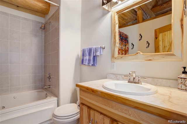 full bathroom featuring vanity, tiled shower / bath combo, and toilet