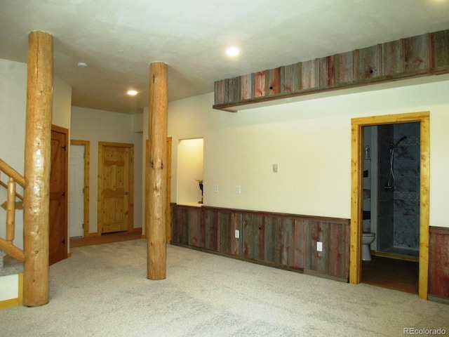 empty room with light colored carpet and wooden walls