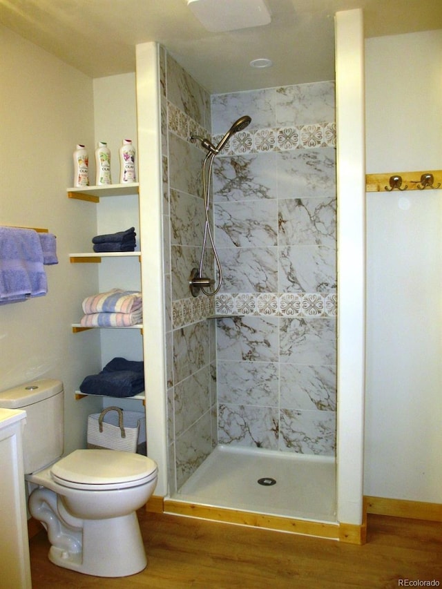 bathroom featuring toilet, wood-type flooring, and tiled shower