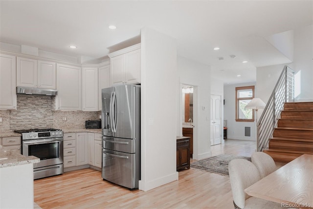 2034 Newton St, Denver, CO 80211 - kitchen with stainless steel appliances, under cabinet range hood, decorative backsplash, light wood-type flooring, and light stone counters