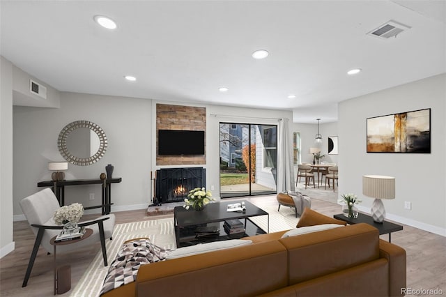 living room with light hardwood / wood-style floors and a stone fireplace