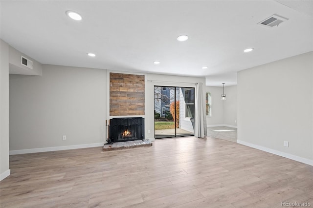 unfurnished living room with a large fireplace and light hardwood / wood-style flooring