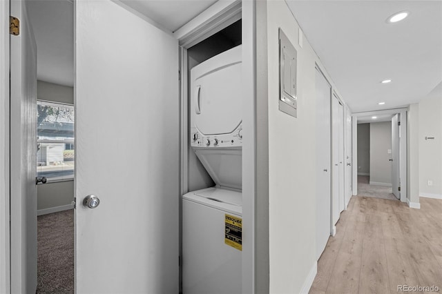 laundry area with light hardwood / wood-style flooring and stacked washer and clothes dryer