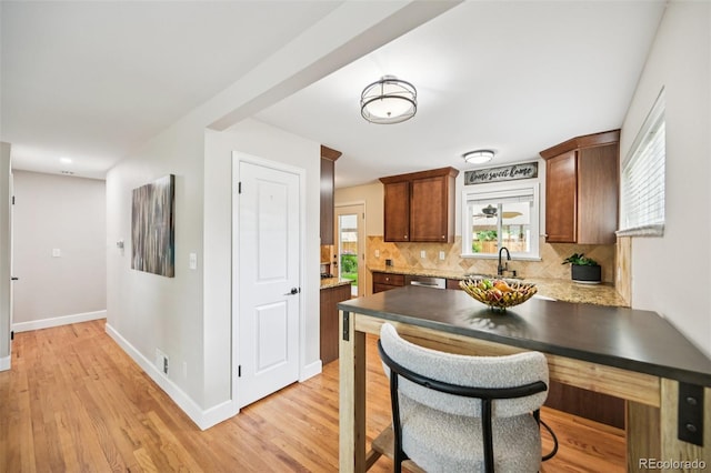 2880 S High St, Denver, CO 80210 - kitchen with tasteful backsplash, light wood finished floors, stainless steel dishwasher, and a peninsula