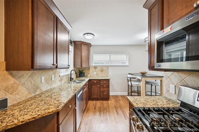 2880 S High St, Denver, CO 80210 - kitchen featuring stainless steel appliances, decorative backsplash, light stone counters, and light wood finished floors