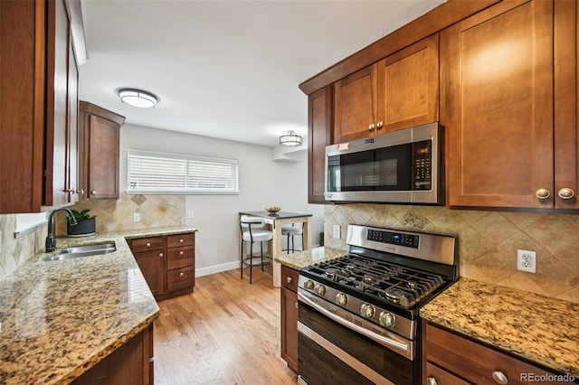 2880 S High St, Denver, CO 80210 - kitchen featuring appliances with stainless steel finishes, backsplash, light stone counters, and light wood-style flooring