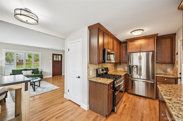 2880 S High St, Denver, CO 80210 - kitchen featuring stainless steel appliances, light wood-style floors, decorative backsplash, and light stone countertops