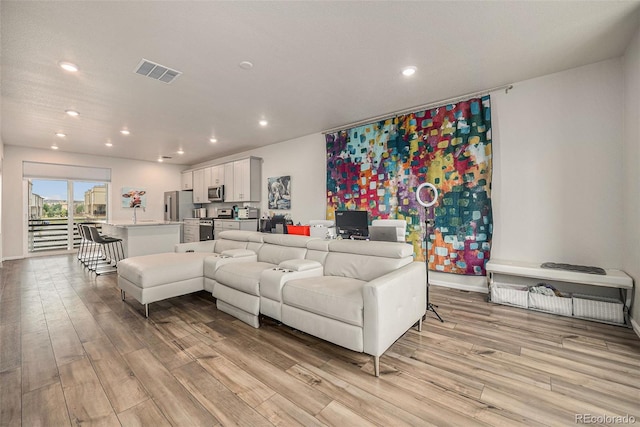 living area with baseboards, recessed lighting, visible vents, and light wood-type flooring