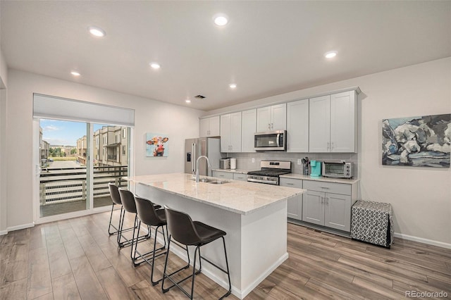 kitchen with tasteful backsplash, an island with sink, a kitchen bar, appliances with stainless steel finishes, and a sink