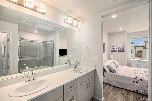 ensuite bathroom with a sink, an enclosed shower, wood finished floors, and double vanity