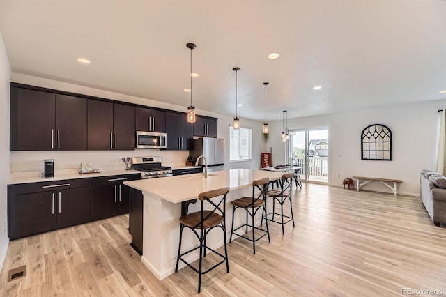 1420 E Witherspoon Dr, Elizabeth, CO 80107 - kitchen featuring stainless steel appliances, a kitchen bar, open floor plan, light wood-style flooring, and light countertops