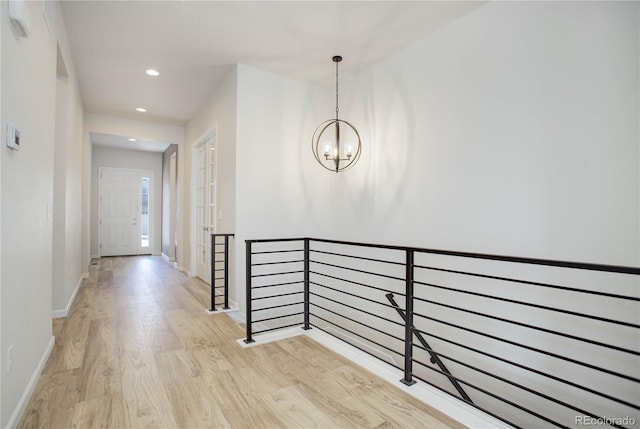 corridor with an inviting chandelier and light hardwood / wood-style floors