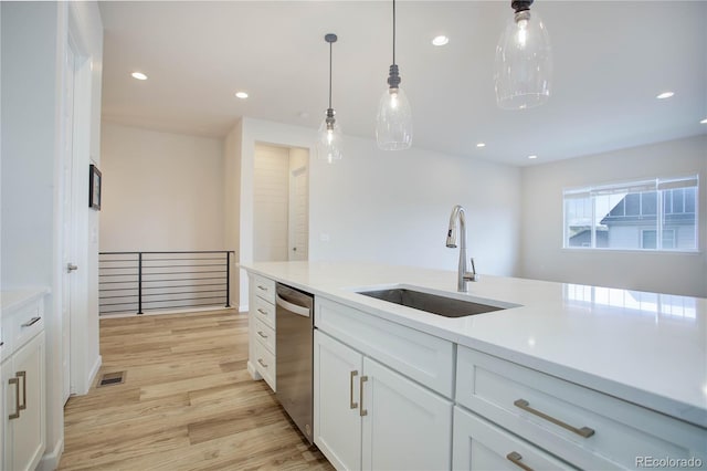 kitchen with white cabinets, hanging light fixtures, light hardwood / wood-style floors, sink, and stainless steel dishwasher