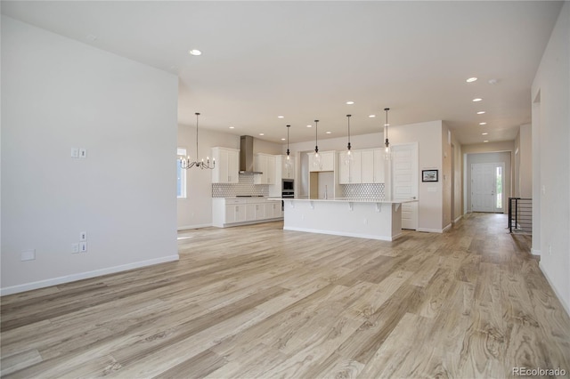 unfurnished living room featuring a chandelier and light hardwood / wood-style floors