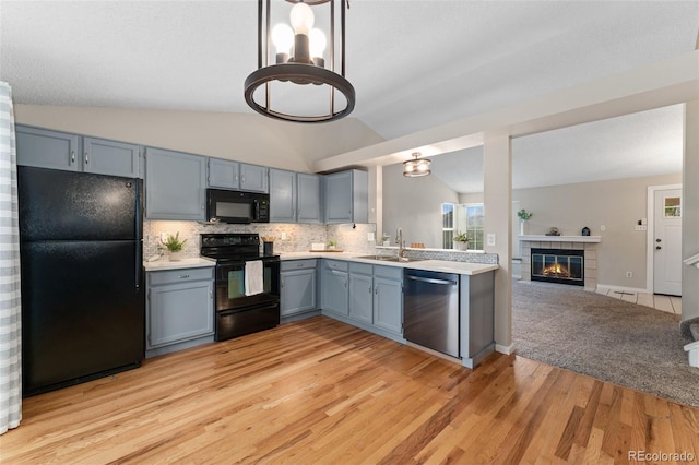 11532 Newland St, Westminster, CO 80020 - kitchen featuring black appliances, light countertops, light wood-style flooring, tasteful backsplash, and vaulted ceiling
