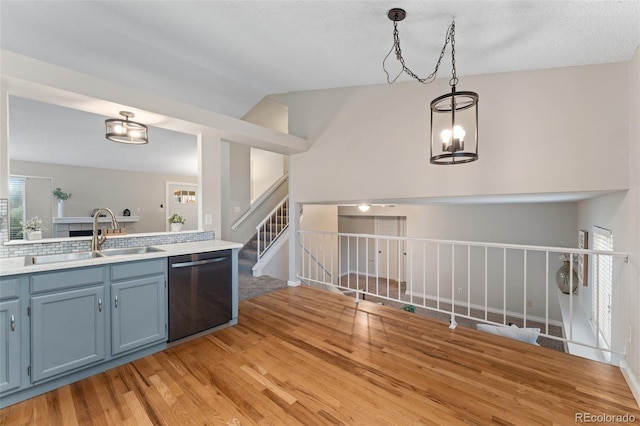 11532 Newland St, Westminster, CO 80020 - kitchen with stainless steel dishwasher, light wood-style flooring, lofted ceiling, decorative light fixtures, and blue cabinets