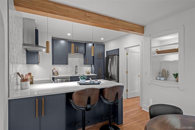 kitchen featuring appliances with stainless steel finishes, a peninsula, a breakfast bar area, blue cabinetry, and light countertops