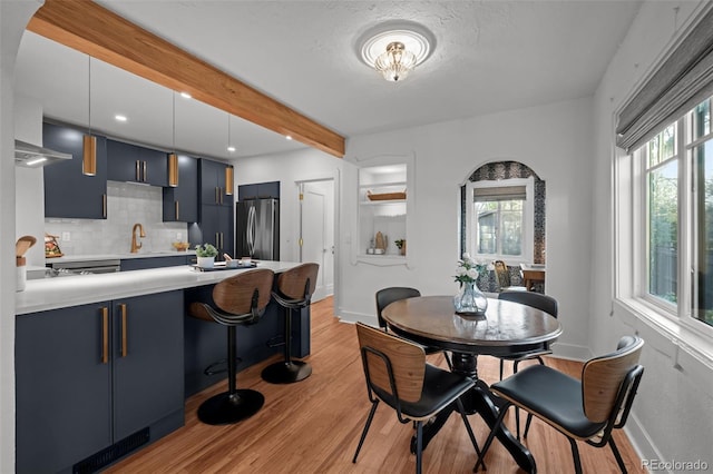 dining room with light wood finished floors, healthy amount of natural light, beamed ceiling, baseboards, and recessed lighting