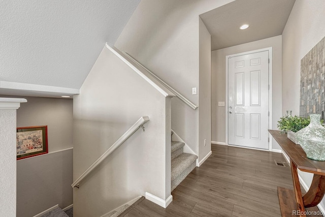 stairs with vaulted ceiling and wood-type flooring