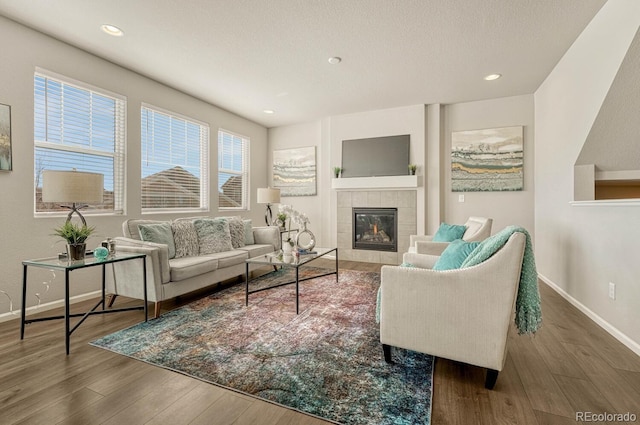 living room with wood-type flooring and a tile fireplace