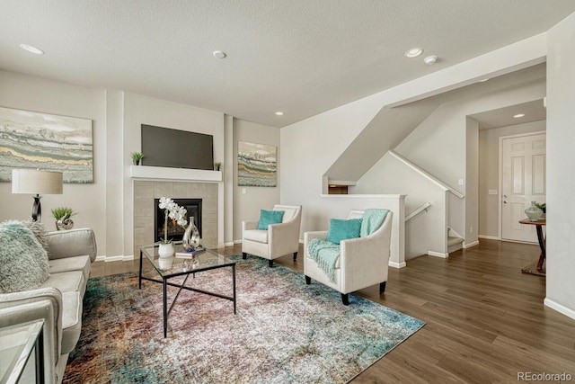 living room with a tiled fireplace, dark hardwood / wood-style flooring, and a textured ceiling