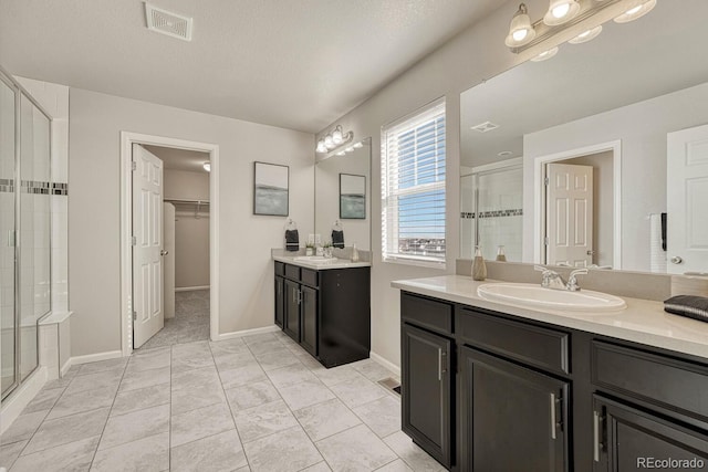 bathroom with a shower with door, vanity, tile patterned floors, and a textured ceiling