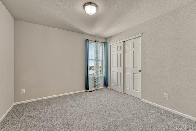 unfurnished bedroom featuring a textured ceiling, a closet, and carpet