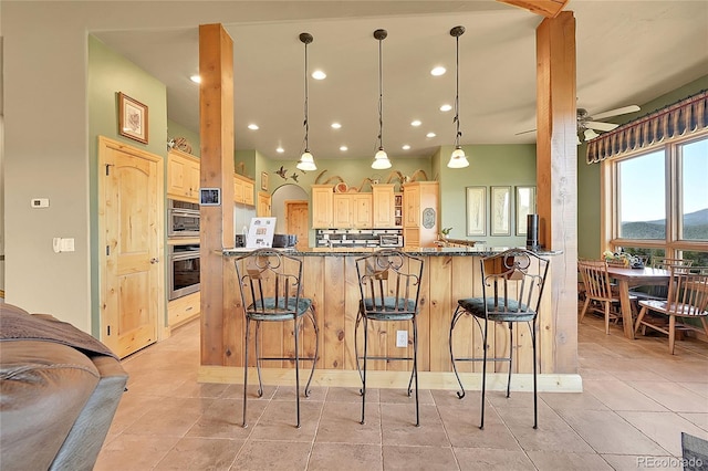 2433 Dogie Spur, Golden, CO 80403 - kitchen featuring oven, light brown cabinetry, a breakfast bar, light tile patterned flooring, and recessed lighting