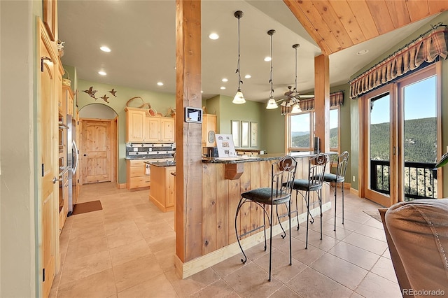 2433 Dogie Spur, Golden, CO 80403 - kitchen with recessed lighting, a breakfast bar, tasteful backsplash, light brown cabinetry, and light tile patterned flooring