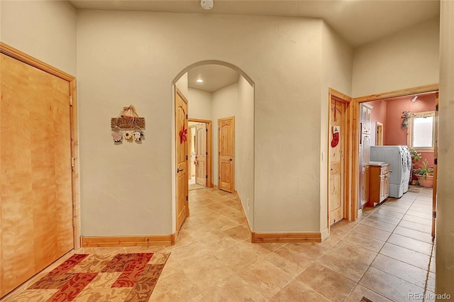 2433 Dogie Spur, Golden, CO 80403 - hallway with arched walkways, washer / dryer, baseboards, and light tile patterned floors