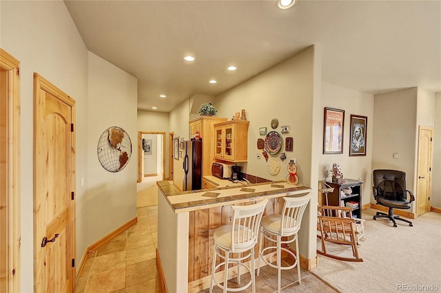 2433 Dogie Spur, Golden, CO 80403 - kitchen with black fridge, a kitchen bar, baseboards, recessed lighting, and glass insert cabinets