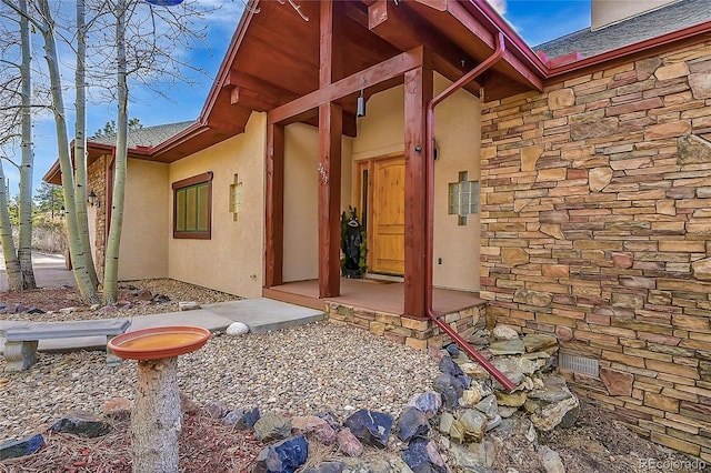 2433 Dogie Spur, Golden, CO 80403 - view of exterior entry with stone siding, stucco siding, and roof with shingles