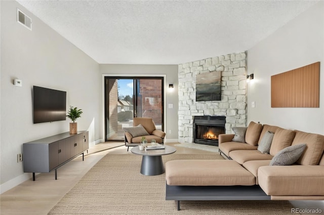 living room with a textured ceiling, a fireplace, and light hardwood / wood-style floors