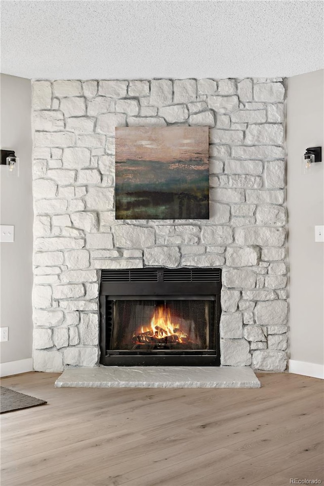 interior details with a stone fireplace, hardwood / wood-style floors, and a textured ceiling