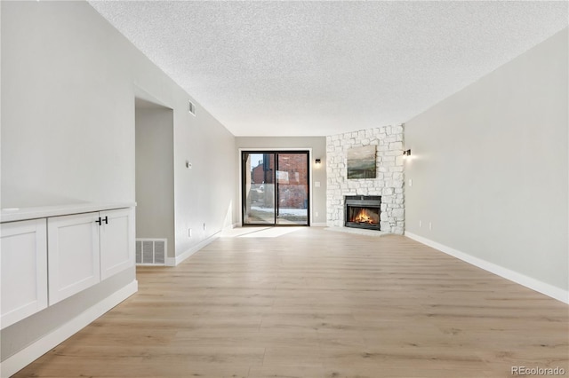 unfurnished living room featuring a fireplace, light hardwood / wood-style floors, and a textured ceiling