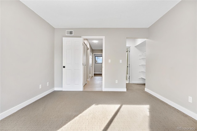 unfurnished bedroom with a spacious closet and light carpet