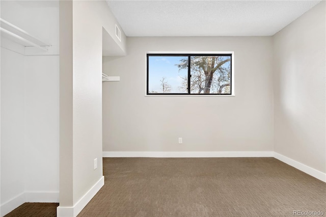 empty room featuring a textured ceiling and dark colored carpet