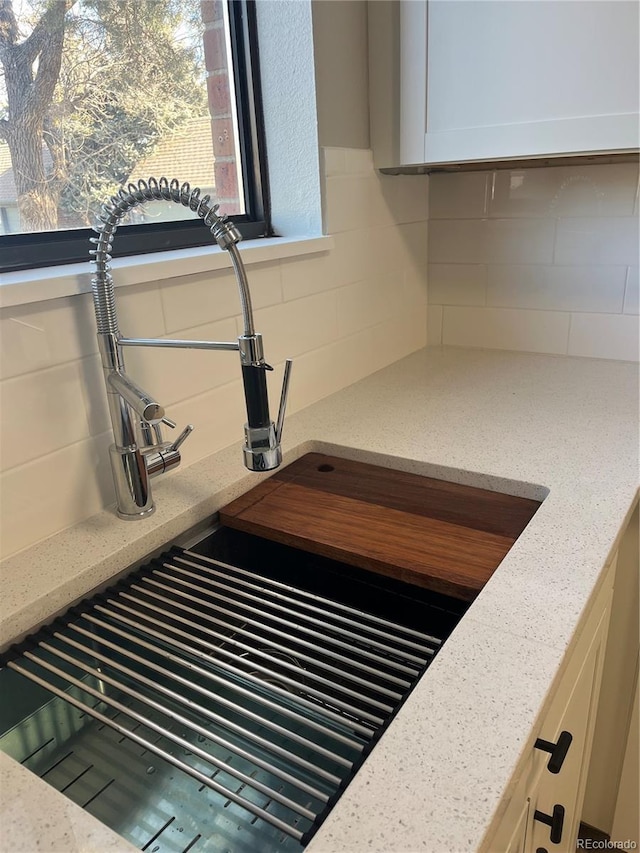 details featuring light stone counters, sink, and decorative backsplash