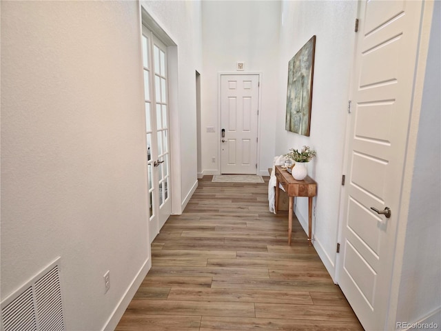 corridor featuring french doors and light wood-type flooring