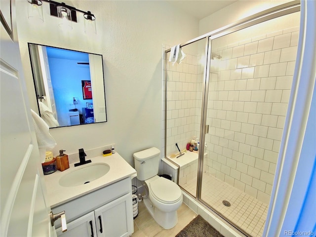 bathroom featuring tile patterned flooring, vanity, toilet, and a shower with door