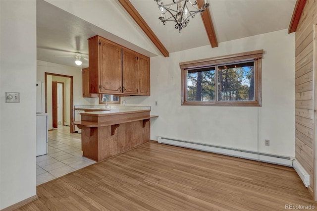 kitchen with vaulted ceiling with beams, a baseboard radiator, light wood-style flooring, a breakfast bar, and brown cabinets