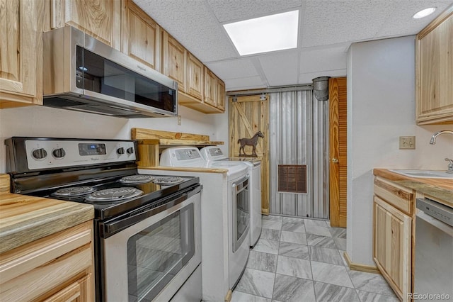 kitchen featuring light countertops, light brown cabinetry, appliances with stainless steel finishes, a sink, and independent washer and dryer