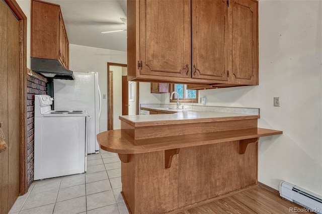 kitchen featuring a baseboard radiator, a peninsula, a breakfast bar, white range with electric stovetop, and brown cabinetry