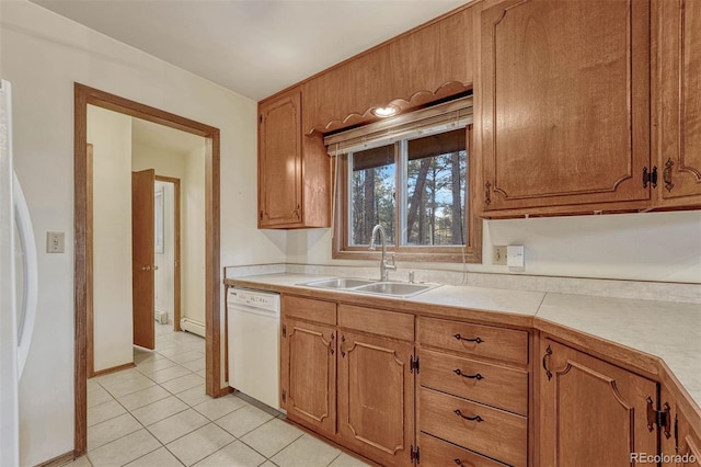 kitchen featuring light countertops, baseboard heating, light tile patterned flooring, a sink, and white appliances