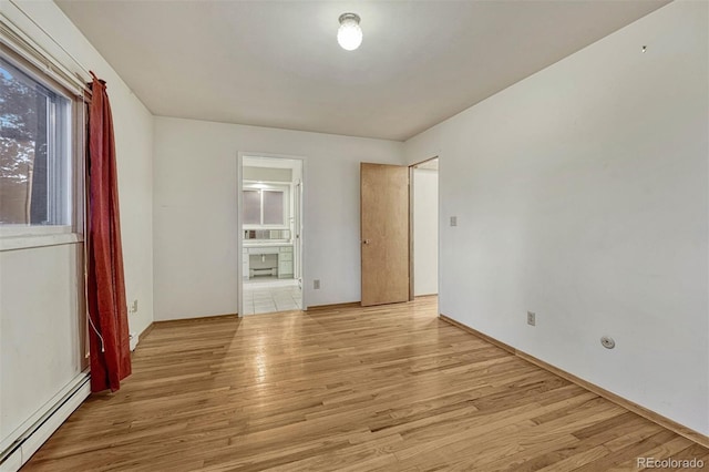 spare room with a baseboard radiator and light wood finished floors